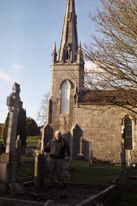 Bill Diederich standing beside the gravestone of Richard Kenefake